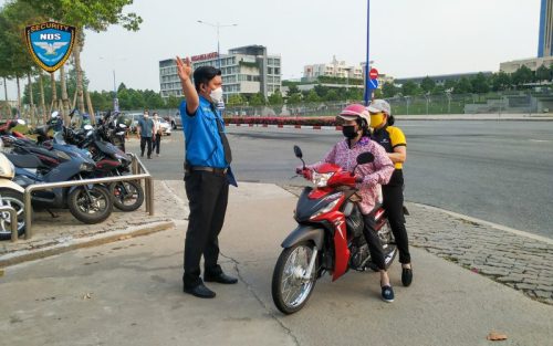 Nhân viên bảo vệ hướng dẫn vị trí đậu xe cho khách vào cổng  